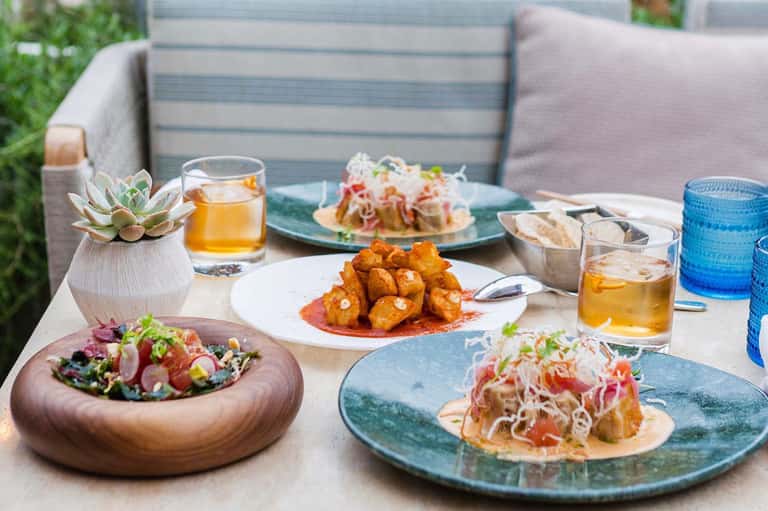 Outdoor dining spread with colorful dishes, cocktails, succulents, and patio seating