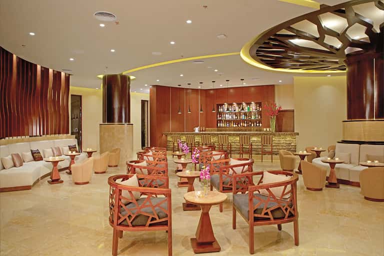 Elegant resort bar and lounge with warm lighting, decorative ceiling, and full bar