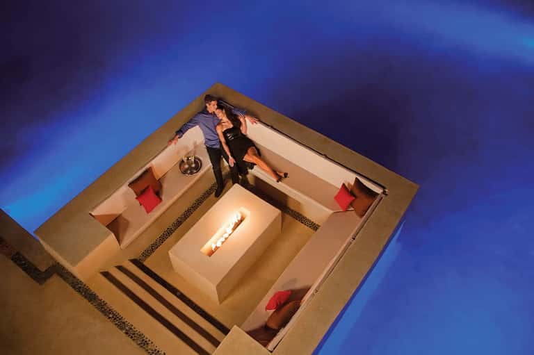 Couple in modern bedroom suite with fireplace viewed from above aerial perspective