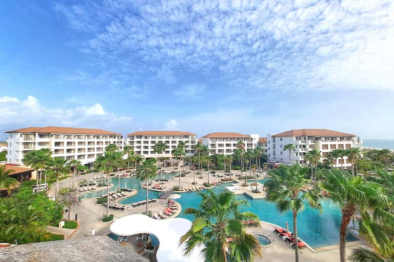 Resort complex with turquoise pools, palm trees, and multi-story white buildings