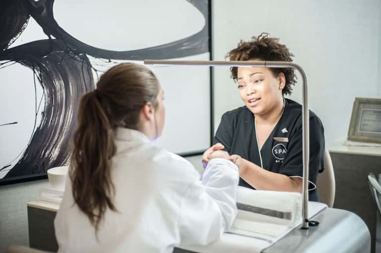 Spa staff member in black uniform assisting guest at reception desk