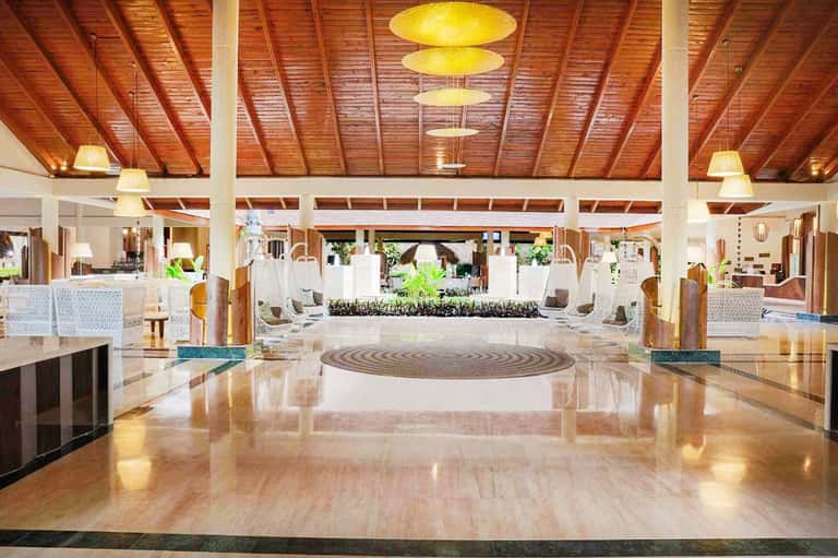 Spacious hotel lobby with high wooden ceiling, marble floors, and modern white furnishings