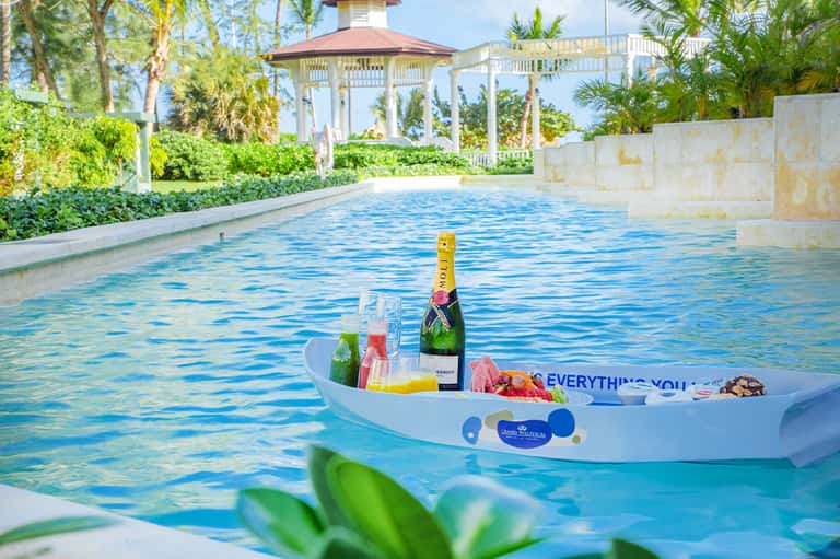 Luxurious pool with floating champagne bar and gazebo, surrounded by lush tropical landscaping
