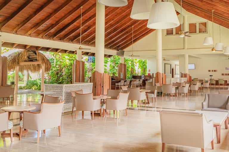 Open-concept resort restaurant and lounge with high wooden ceiling and tropical decor