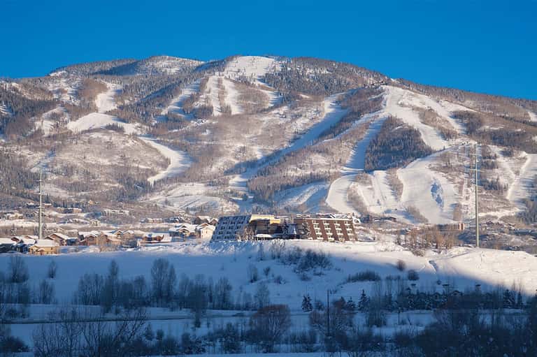 Snow-covered ski mountain with multiple runs and lodge building at base in winter