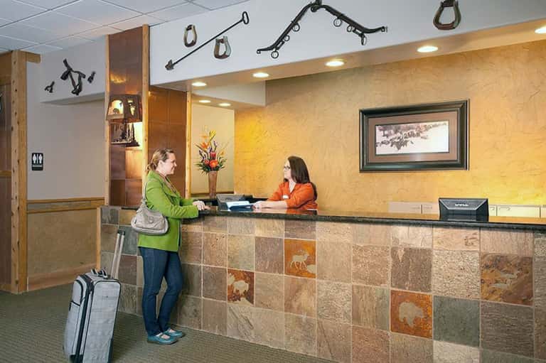 Hotel front desk with staff member checking in guest with rustic tile accent wall