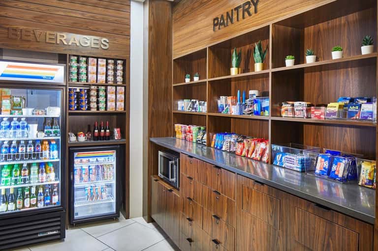 Resort beverage and pantry area with refrigerated drinks display and wooden shelving with snacks