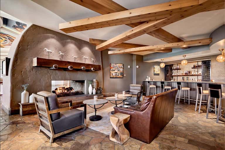 Modern resort lounge with fireplace, exposed wood beams, bar area, and contemporary furnishings