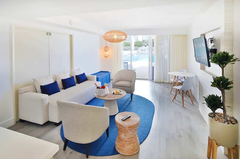 Modern resort suite with white sofa, blue accents, and direct beach access