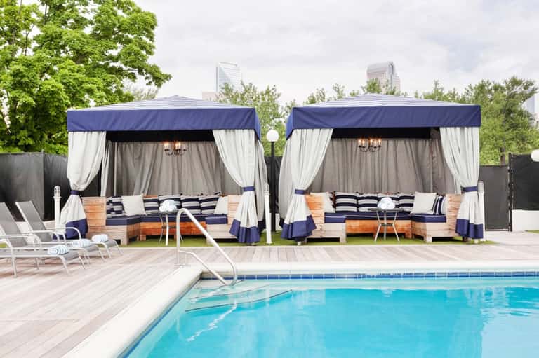 Luxury pool cabanas with navy and white striped cushions beside swimming pool with lounge chairs