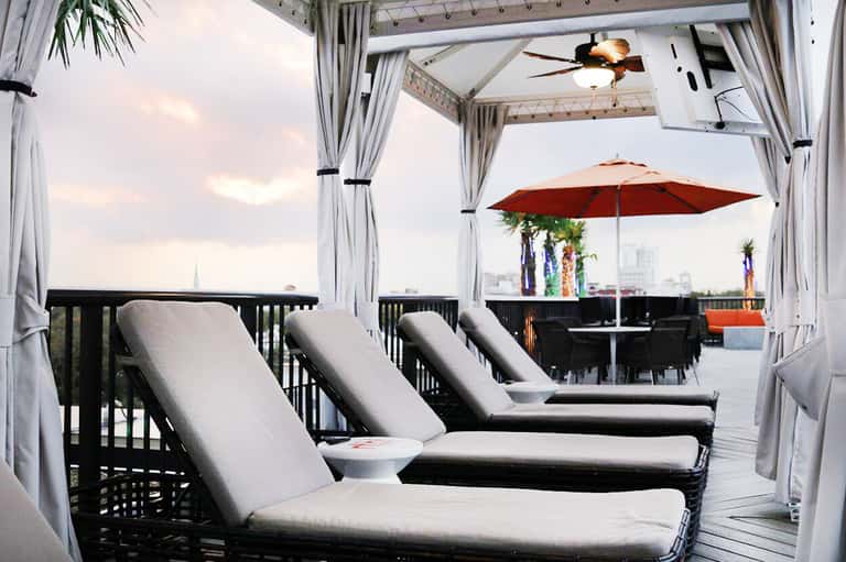 Modern rooftop lounge with daybed, curtains, umbrella, and city skyline view