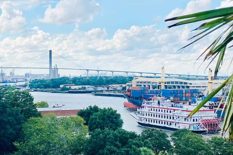 Cargo ship docked at industrial port with suspension bridge in background