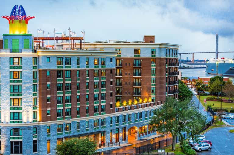 Colorful waterfront hotel building with distinctive turquoise and blue facade near industrial port area