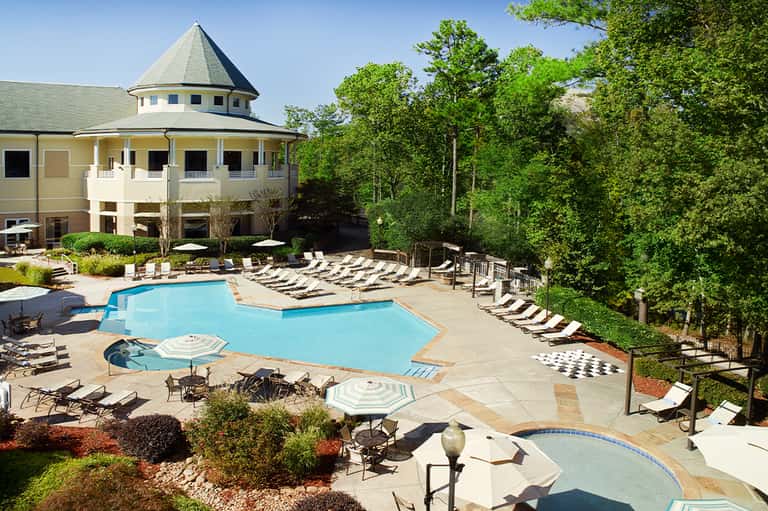 Resort pool with tower building, lounge chairs, and lush forest surroundings