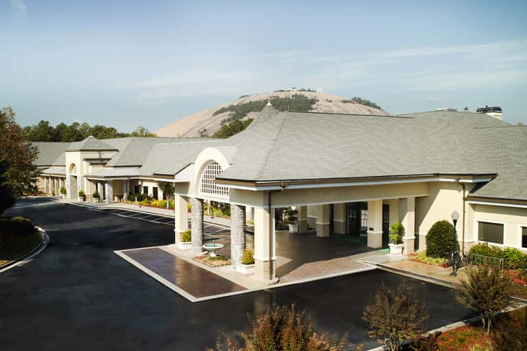 Modern cream-colored resort entrance with arched architecture and manicured landscaping