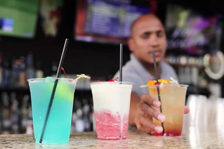 Bartender pouring colorful tropical cocktails with blue, pink, and amber colored drinks