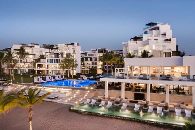 Luxury beachfront resort complex at dusk with pools, modern architecture