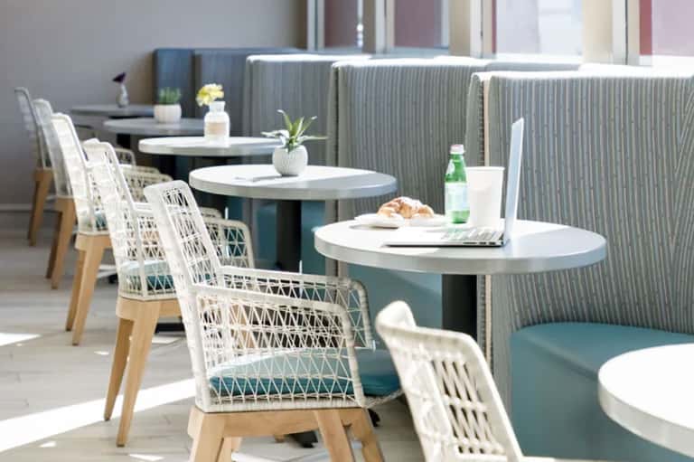 Modern indoor lounge with white woven chairs and teal booth seating