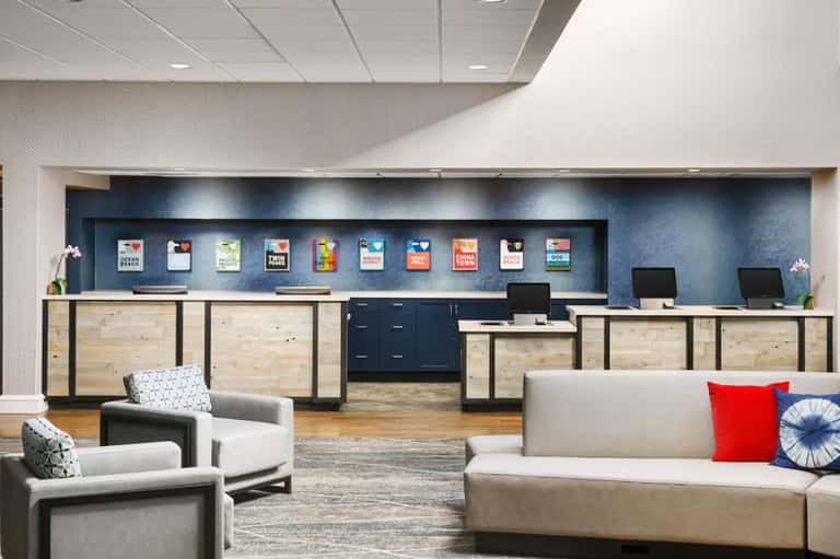 Contemporary hotel lobby with wooden reception desk, seating areas, and accent lighting