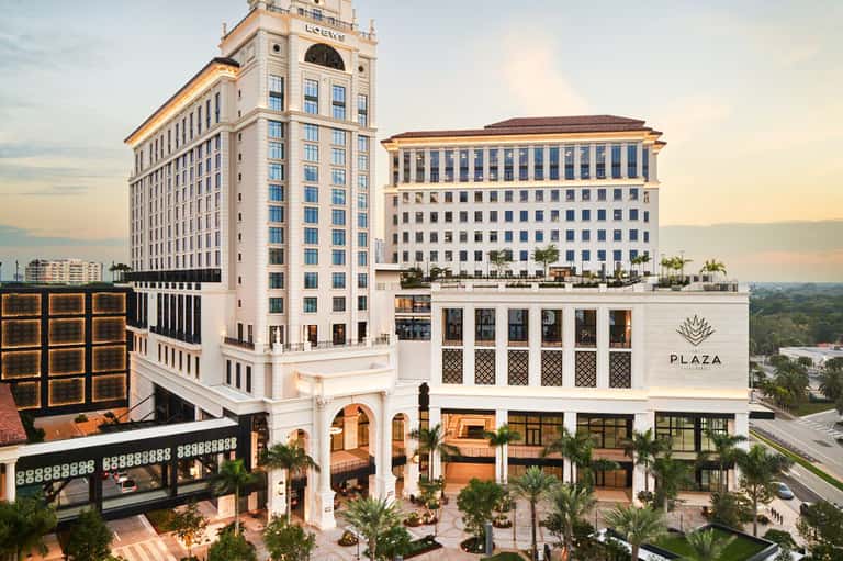 Elegant historic hotel plaza with white columns and palm trees at sunset