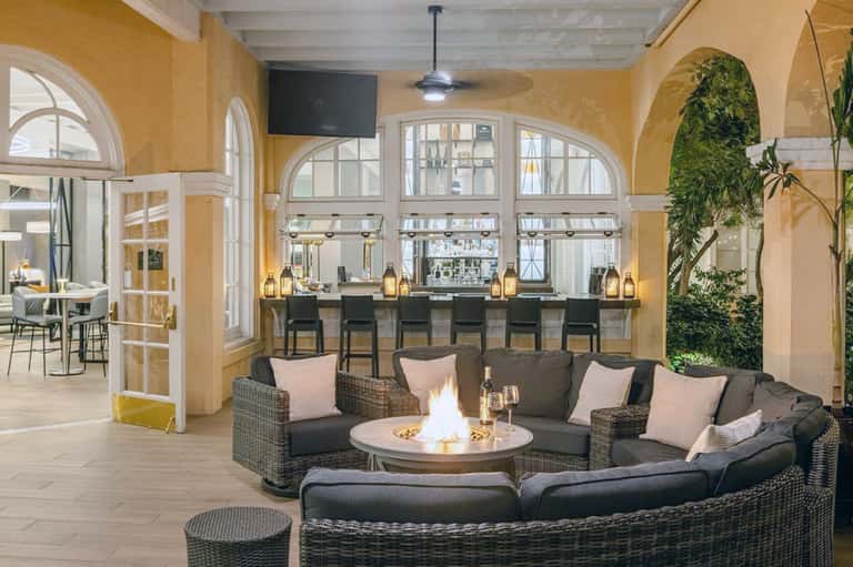 Elegant lounge with bar, fireplace, hanging plants, and arched windows