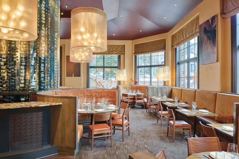 Upscale restaurant interior with wooden accents, pendant lights, and dining tables
