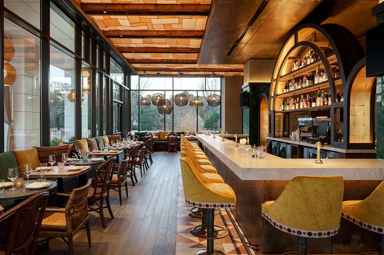 Upscale restaurant with wooden beams, arched wine display, and large windows