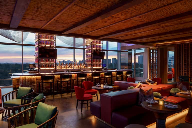 Upscale bar lounge with city skyline views, wooden ceiling, and colorful seating