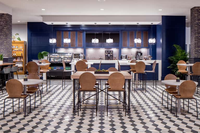 Modern hotel cafe with navy cabinetry, pendant lighting, and dining seating in contemporary design