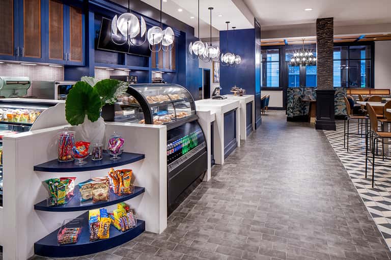 Modern hotel café interior with blue cabinetry, bakery display, and pendant lighting