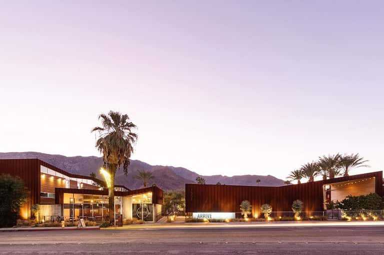 Modern desert resort entrance at dusk with warm lighting and palm trees