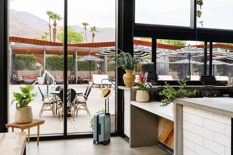 Resort lobby and lounge area with large windows overlooking palm trees and mountains