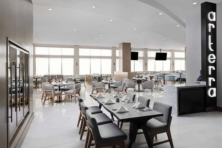 Contemporary restaurant dining room with floor-to-ceiling windows and modern place settings
