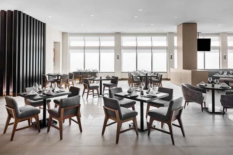 Upscale dining room with black tables, modern chairs, floor-to-ceiling windows, contemporary design
