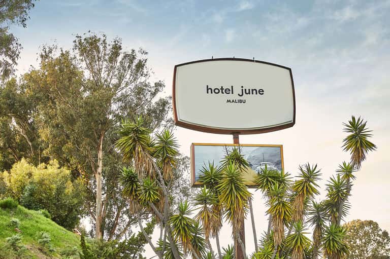 Hotel June Malibu vintage sign with palm trees against cloudy sky