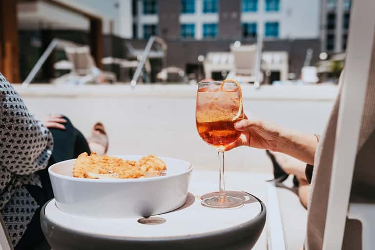 Outdoor rooftop area with cocktail drink and snacks on table with urban views