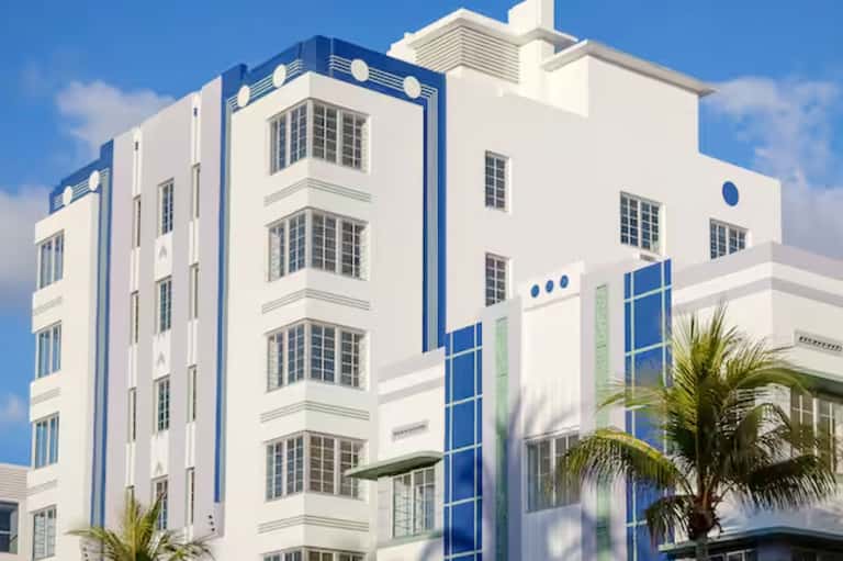 Art deco style hotel building facade in white and blue with palm trees