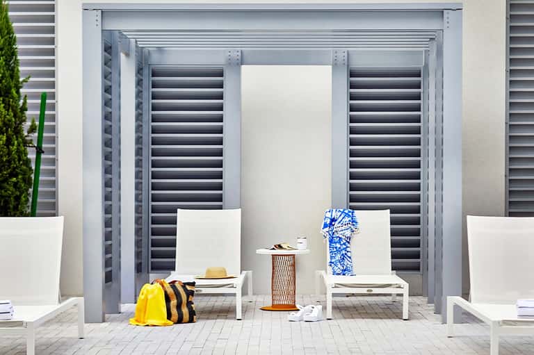 Modern poolside cabana with white lounge chairs and dark shuttered doors