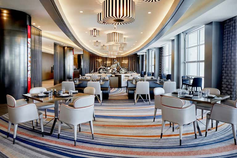 Upscale dining room with curved ceiling, decorative pendant lights, striped carpet, and formal table settings