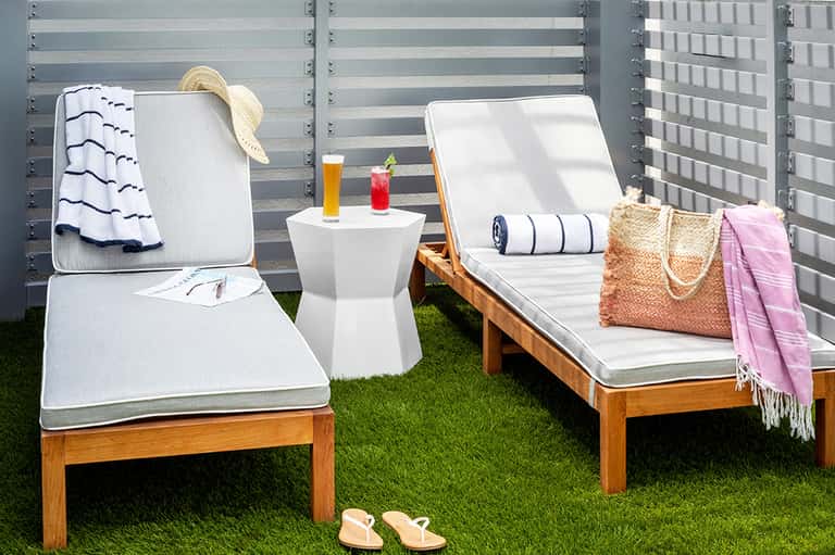 Rooftop lounge seating with wooden chaise lounges, white cushions, and metal privacy screens