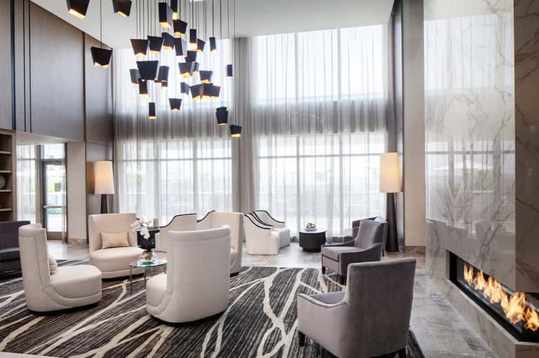 Modern hotel lobby with high ceilings, hanging pendant lights, and contemporary seating