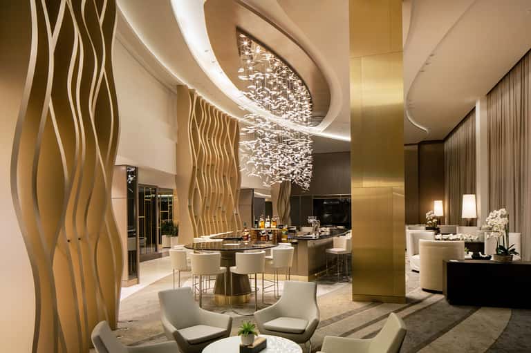 Modern luxury hotel lobby with gold accents, curved ceiling, and contemporary furnishings