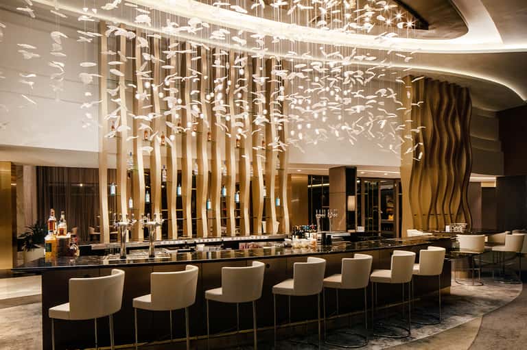 Elegant hotel bar with sculptural white pendant lighting installation and black granite counter
