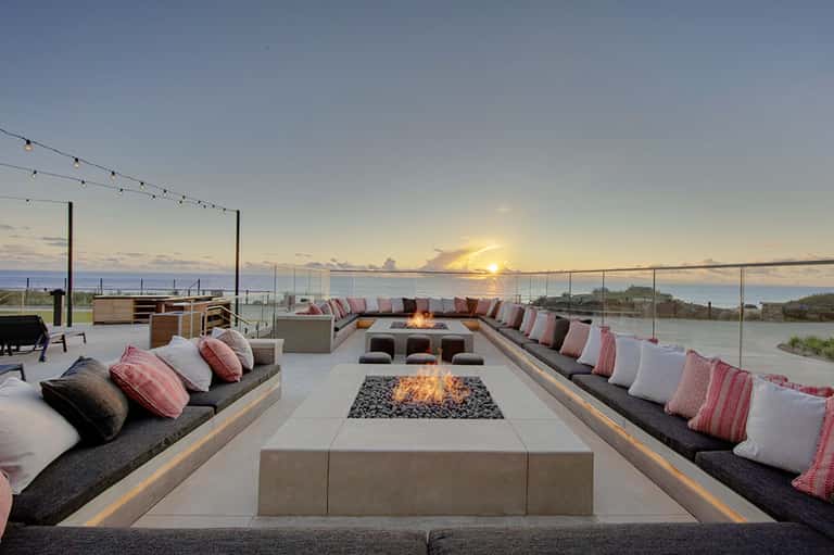 Sunset fire pit lounge with built-in seating, cushions, and waterfront views