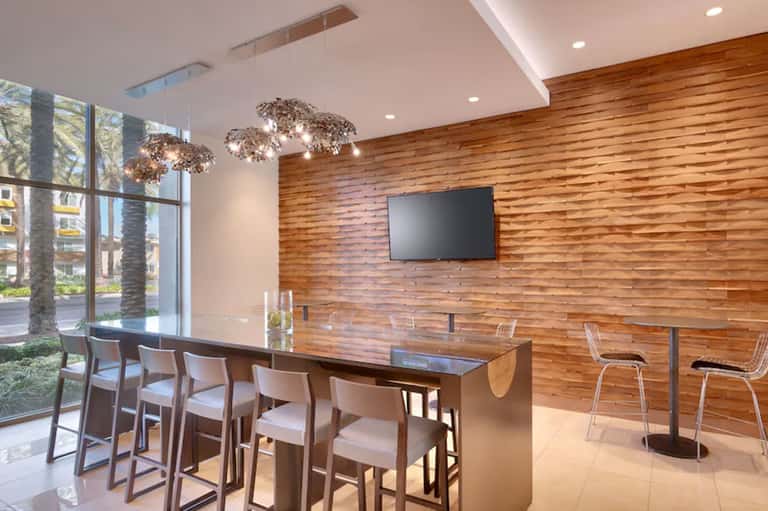 Contemporary lounge area with wooden wall, hanging pendant lights, and high-top bar seating