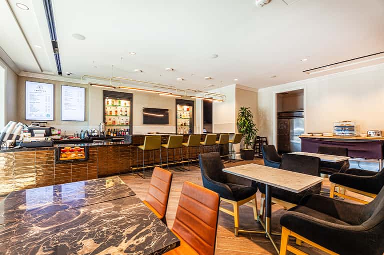 Contemporary hotel bar and lounge with bronze chairs, bar seating, and warm lighting