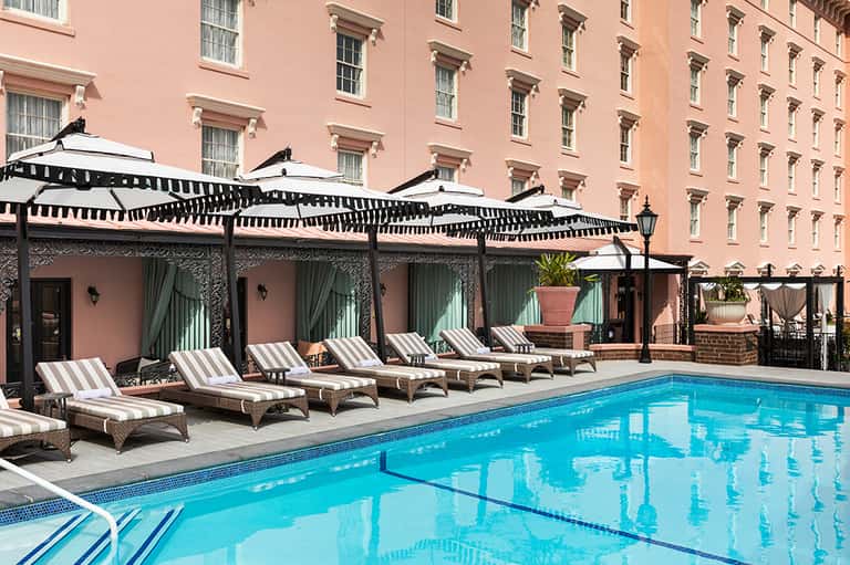 Elegant poolside lounge with striped loungers under black pergolas at luxury resort