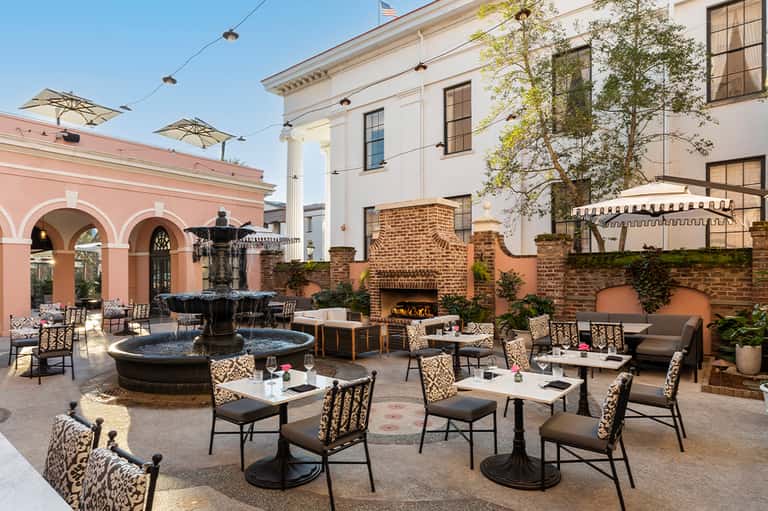Upscale courtyard with fountain, fireplace, and sophisticated seating areas surrounded by architecture