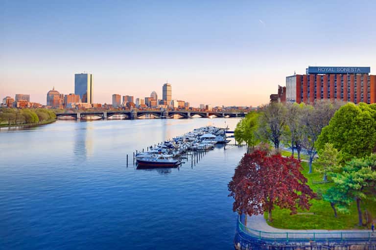 Boston waterfront with historic bridges, boats docked along river, and Royal Sonesta hotel building