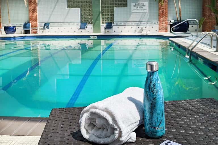 Swimming pool with lane markings, white towel and blue water bottle on dark poolside